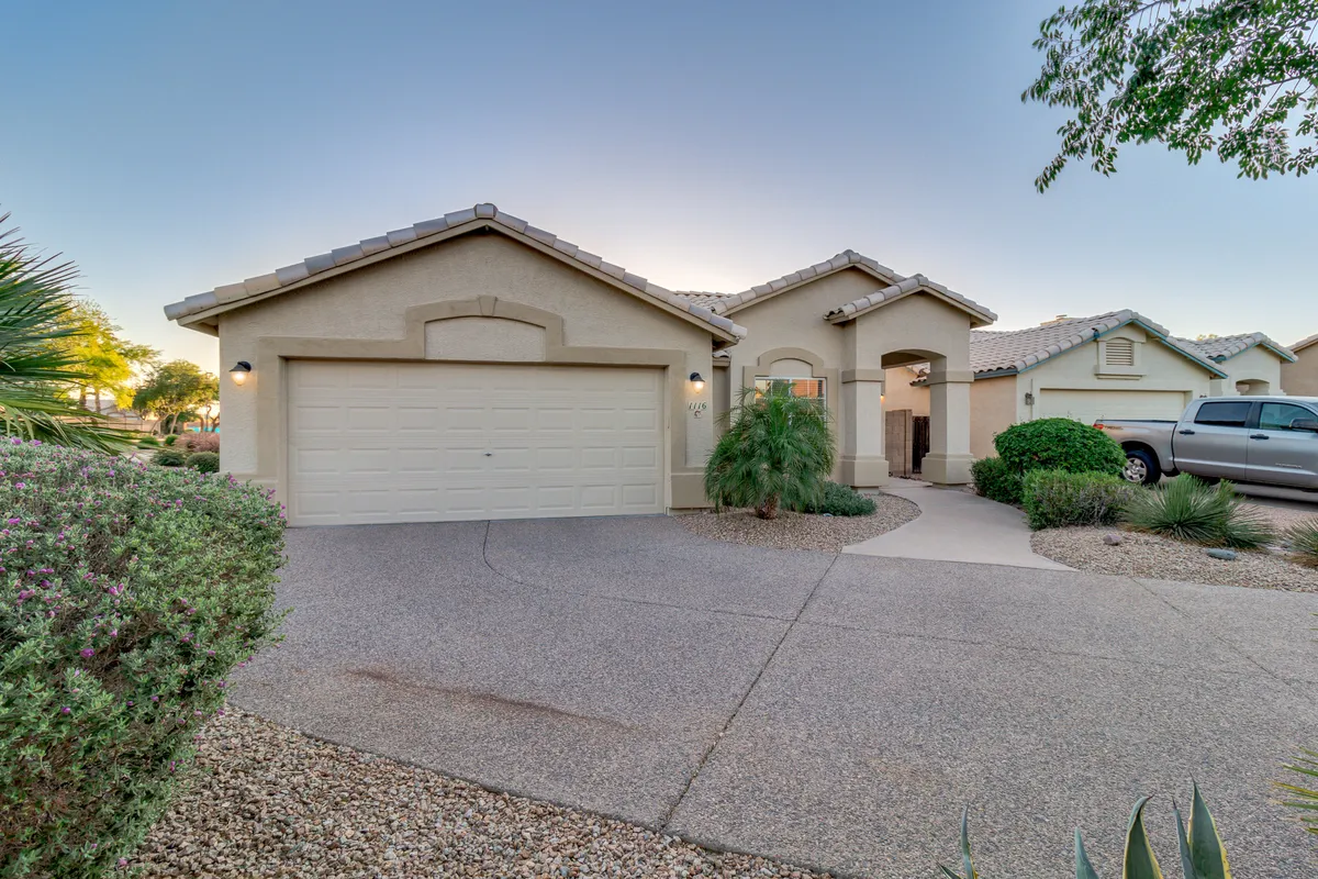 A welcoming exterior view showing the front door, garage, and neatly landscaped yard. The setting is casual and friendly, suggesting a sense of arrival and community engagement.