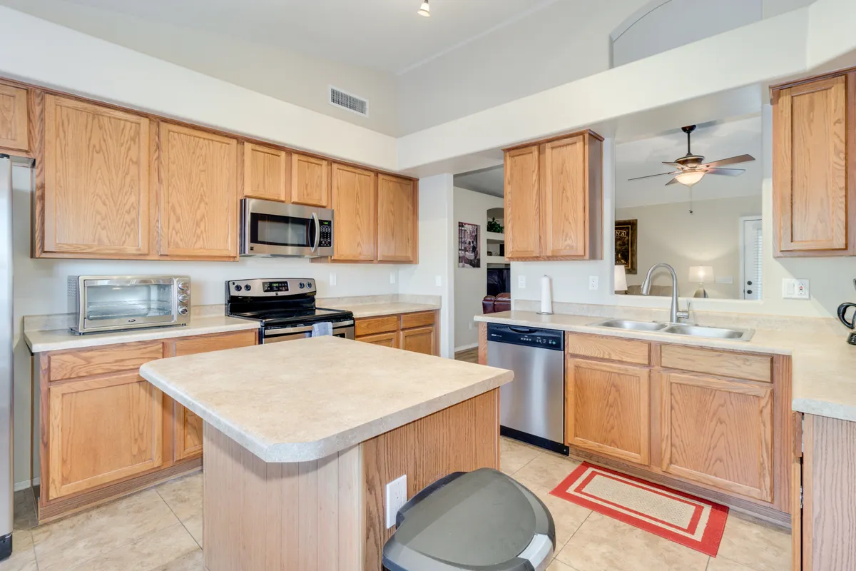 A welcoming eat-in kitchen featuring a spacious kitchen island, gleaming stainless steel appliances, and warm wood cabinetry. The room is well-lit, with plenty of workspace and modern finishes that create an inviting atmosphere for both cooking and gathering.